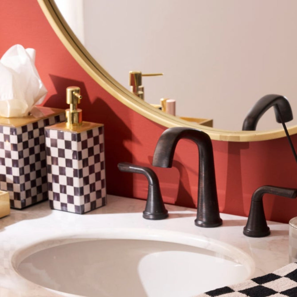 Bathroom sink with black faucet and mirror on a red wall