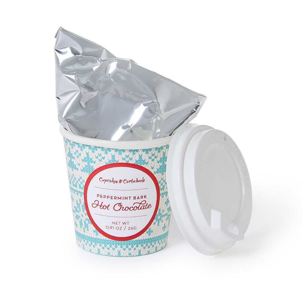A close up of one of the hot chocolate cups "Peppermint Bark 0.91 oz"  from the box showing the hot chocolate matalic packaging in a blue and white cup with a label in red on with a red edge on a white backround. 