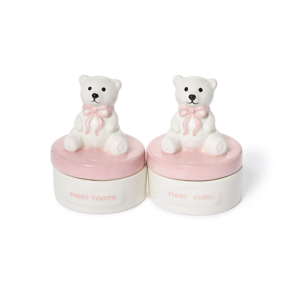 Two small white ceramic bear-shaped hair styling containers with pink lids and bows, labeled 'FIRST TOOTH' and 'FIRST CURL' on a white background.