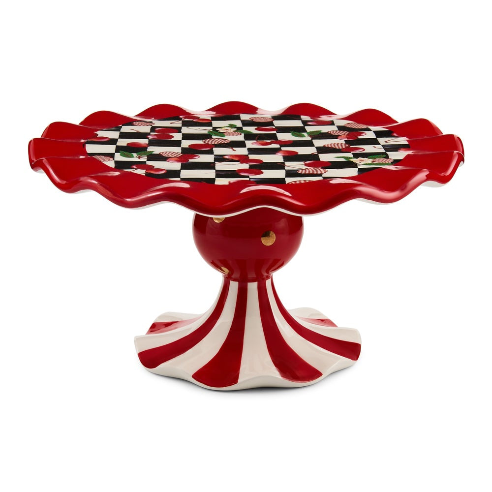 A red and white ceramic pedestal table with a scalloped rim, featuring a black and white checkered top pattern with red cherub motifs, set against a plain white background.