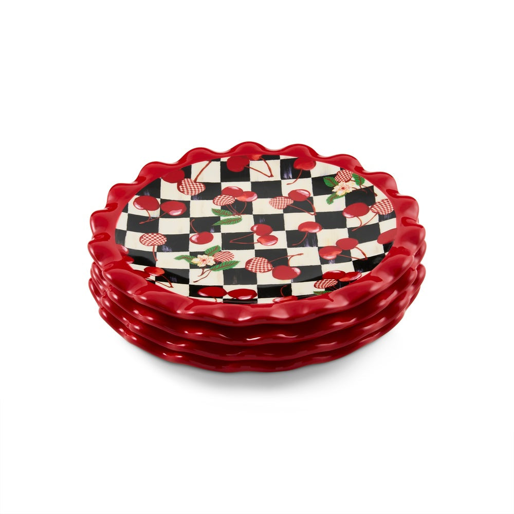 A stack of five ceramic appetizer plates with scalloped red rims, featuring a black and white checkered pattern with red cherries and green leaves on the inner surface, set against a plain white background.
