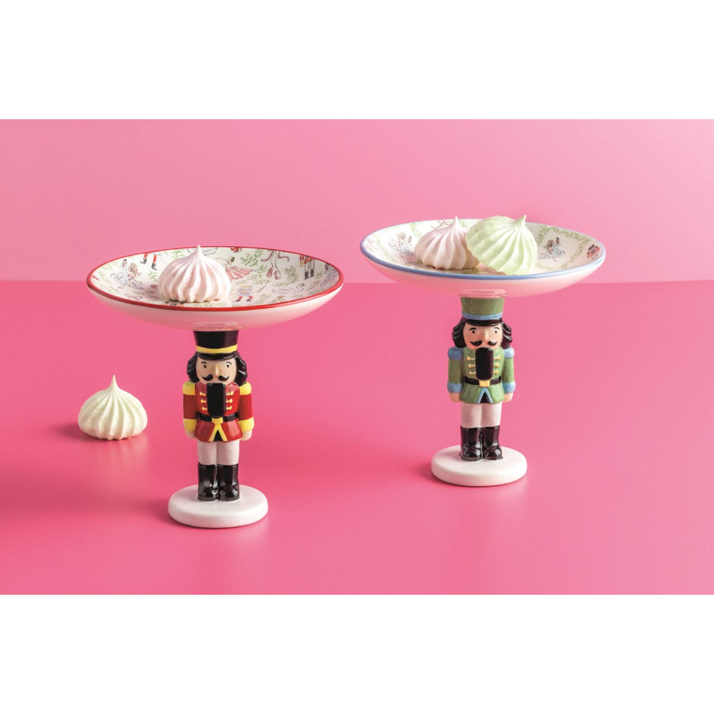 Two decorative nutcracker stands with meringues on a pink background