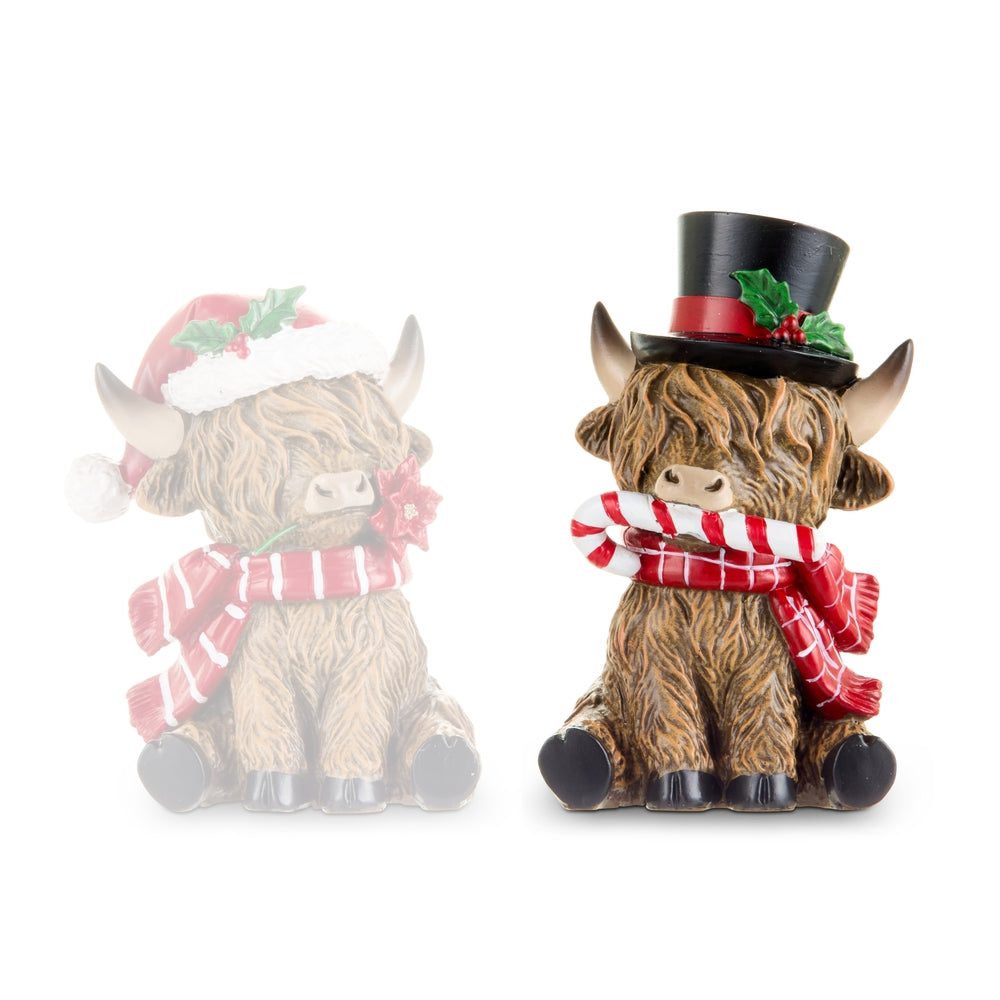 Two decorative Highland cow figurines with festive accessories on a white background