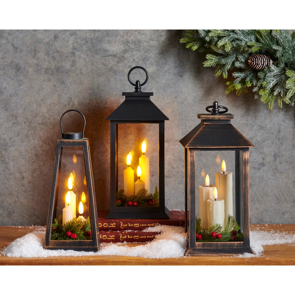 Three lit lanterns with candles on a wooden surface, decorated with greenery and small red berries against a textured wall.