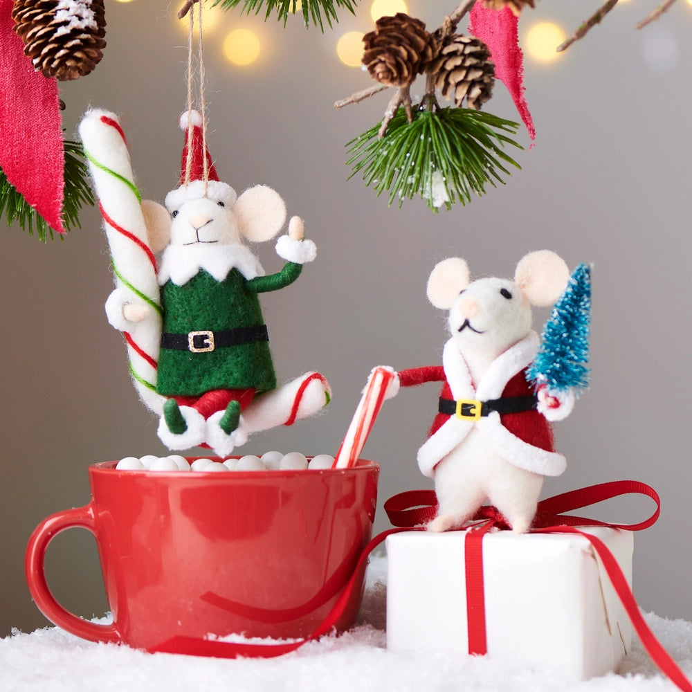 Two Christmas-themed mouse figurines near a red mug with candy canes, surrounded by festive decorations.