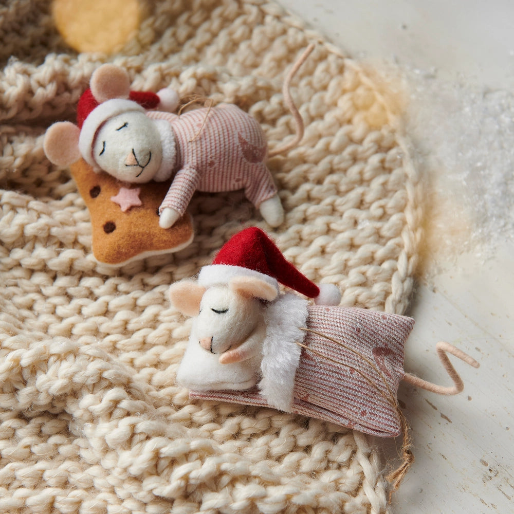 Two small plush ornaments resembling mice in Santa hats on a textured surface.