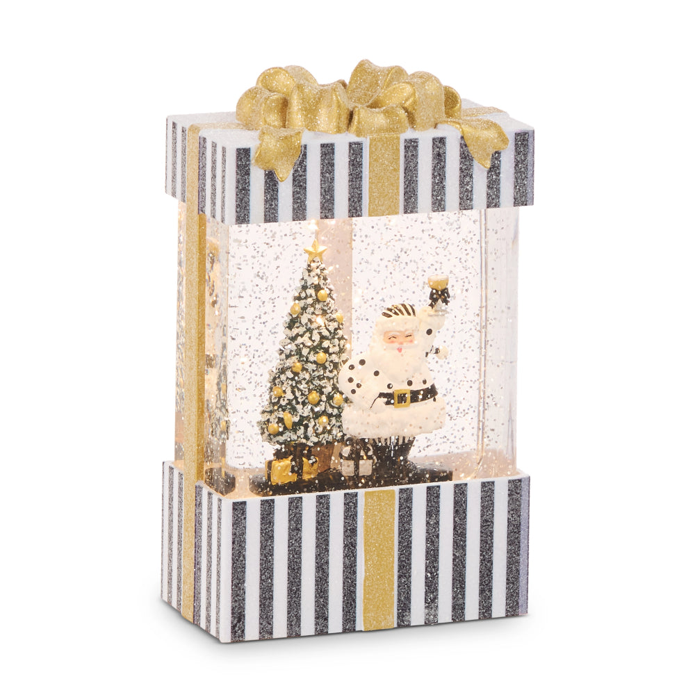 A Christmas-themed gift box themed snowglobe decoration featuring a clear window with a glittery Santa Claus and decorated tree inside, topped with a gold bow, on a white background.