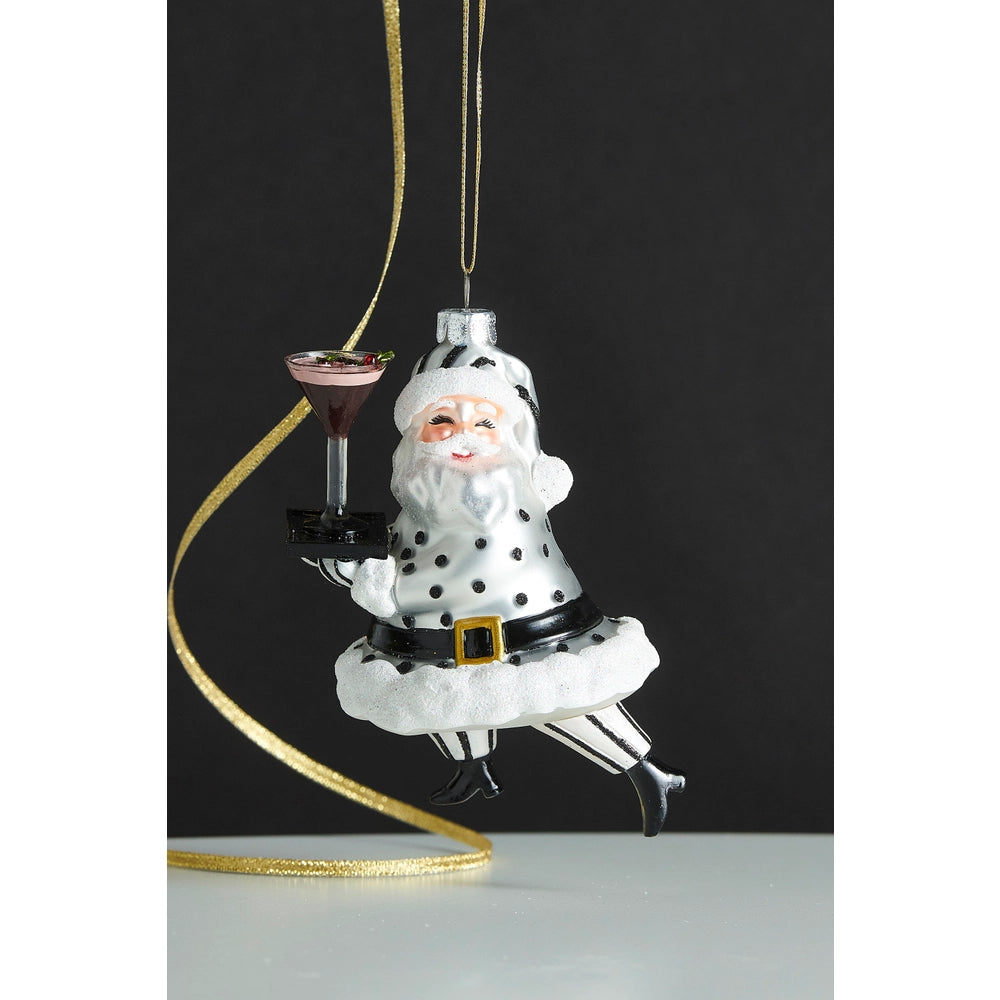 Decorative Christmas ornament of a modern Santa Claus holding a cocktail, hanging from a gold ribbon against a black background.
