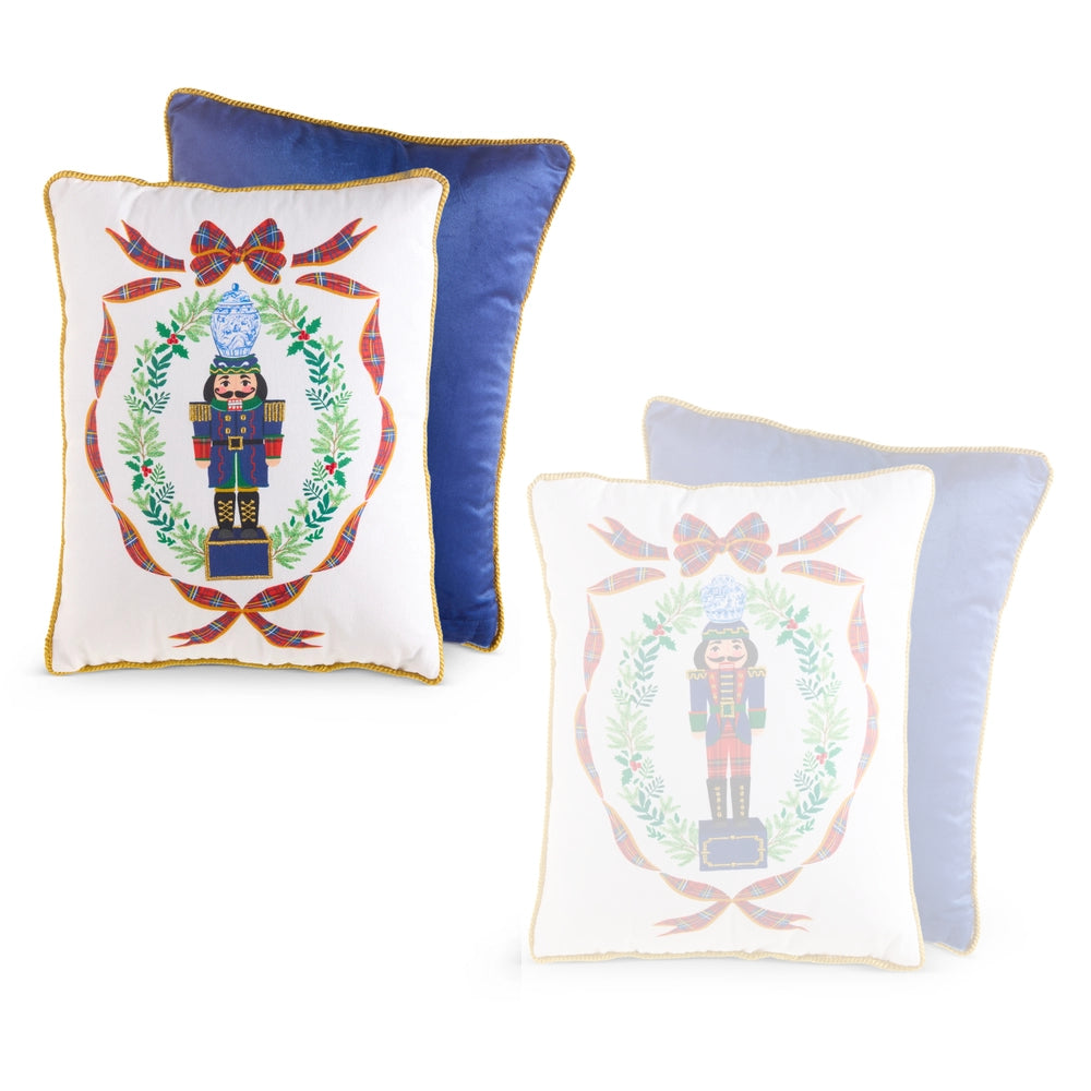 Three decorative throw pillows on a white background: two white pillows with gold trim and a nutcracker emblem, one blue pillow, and one pale blue pillow with a faded nutcracker design.