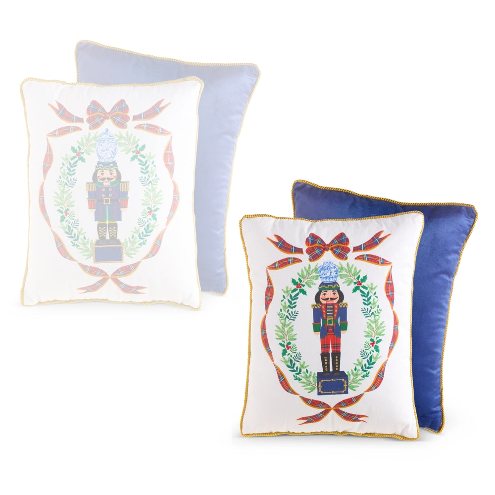 Three decorative throw pillows on a white background: two white pillows with embroidered nutcracker designs and gold trim, and one blue pillow behind them.