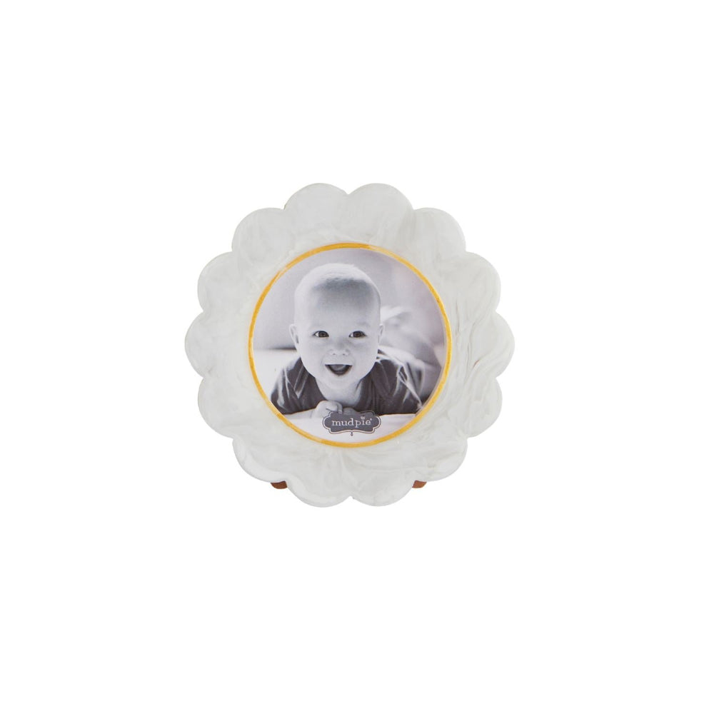 A round scalloped white ceramic picture frame with a gold inner border holding a black-and-white photo of a smiling baby, shown on a plain white background.