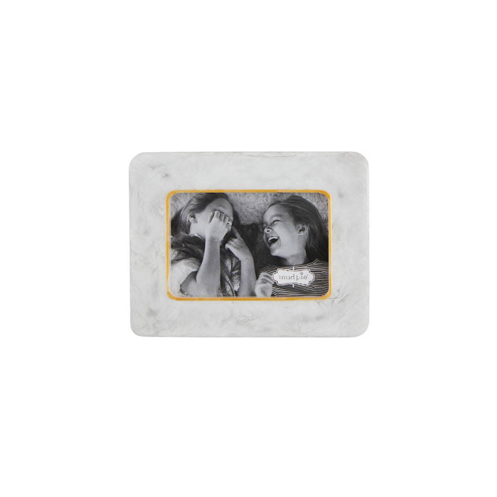 A square white marble picture frame with a gold inner border, displaying a black and white photo of two laughing children. The frame is centered on a solid white background.