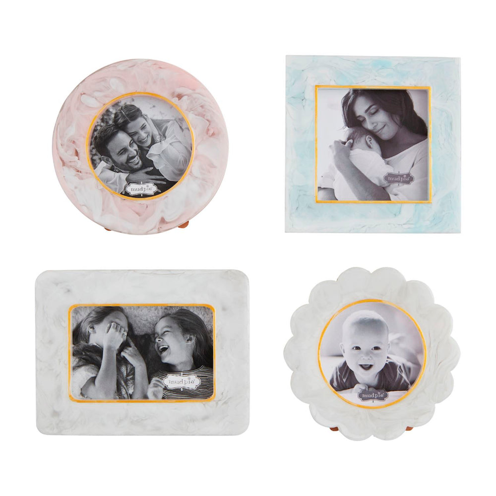 Four decorative picture frames arranged on a white background: a round pink marble frame, a square light blue marble frame, a rectangular white marble frame, and a scalloped white marble frame. Each frame displays a black-and-white sample photo with a gold inner border.