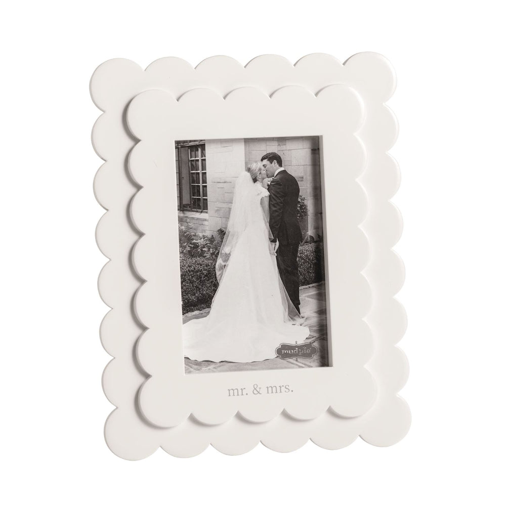 White scalloped photo frame with a black and white photo of a couple labeled 'mr. & mrs" on a white backround. 