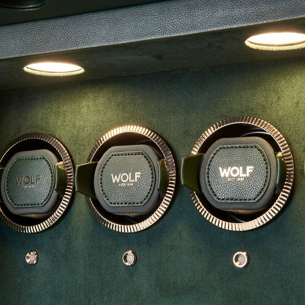 Three Wolf brand watch winders holders on a green vault.