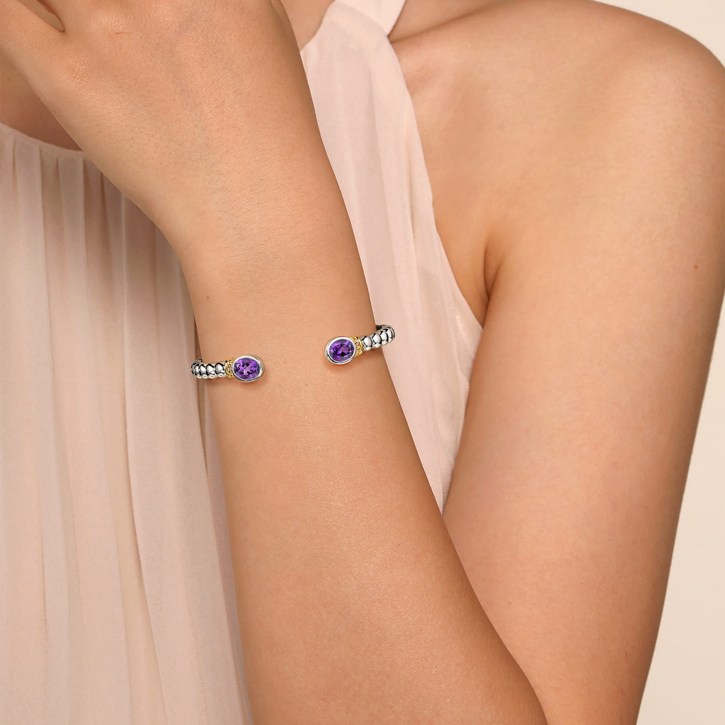 Bracelet with purple gemstones on a person's wrist against a soft pink background