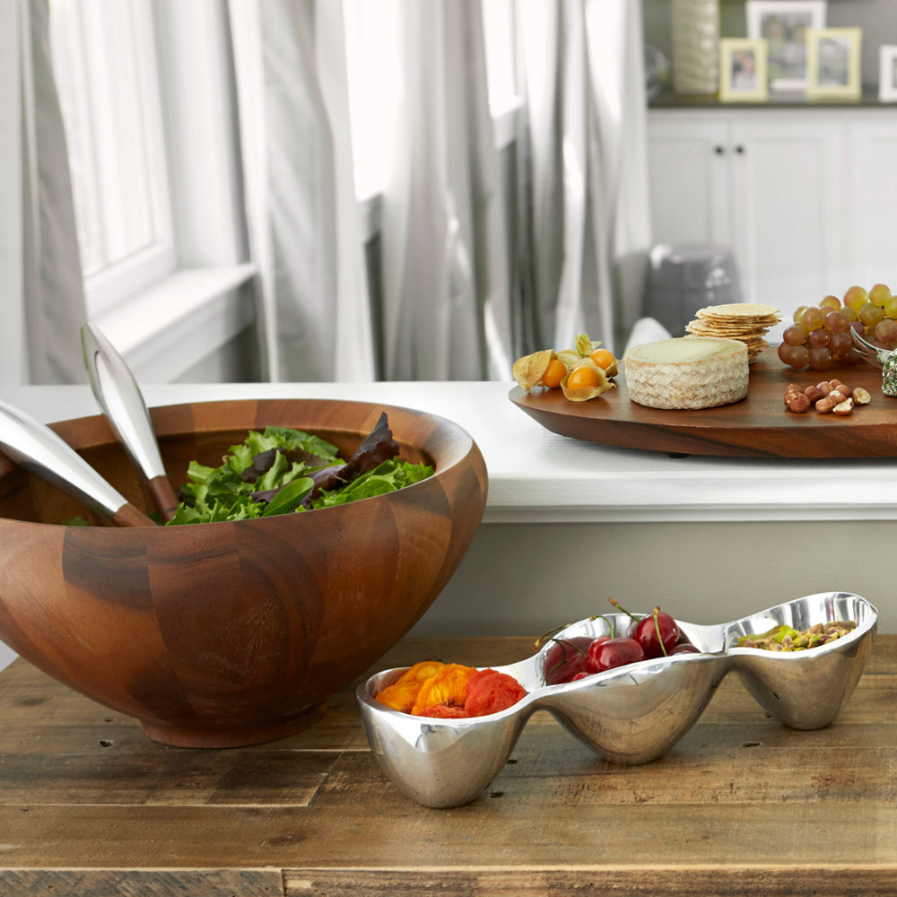 Salad bowl with servers in kitchen setting with chacuterie board. 