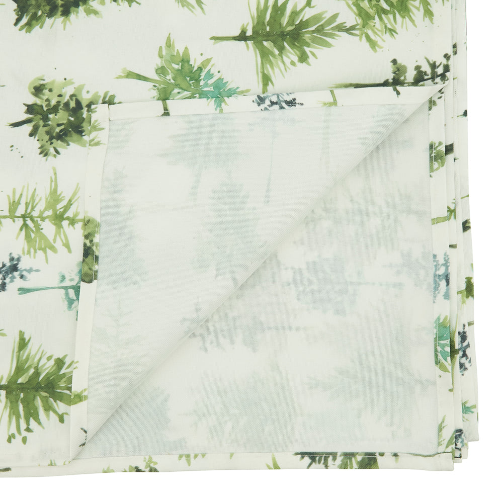 A folded fabric item, likely a blanket or throw, featuring a watercolor-style green fern pattern on a white background, with the underside showing a pale sage green forest print.