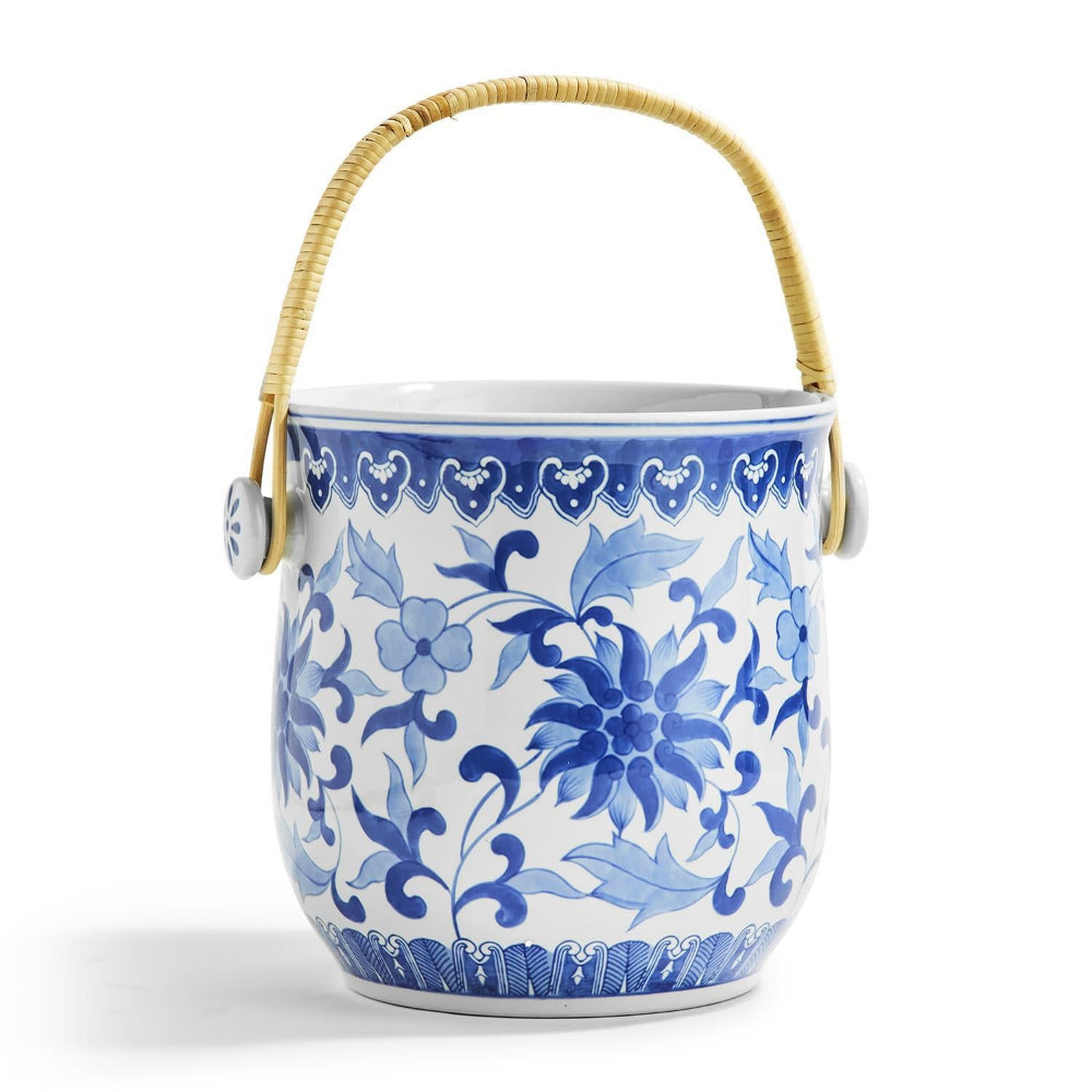 Ceramic bucket with blue floral patterns and a wicker handle on a white background.