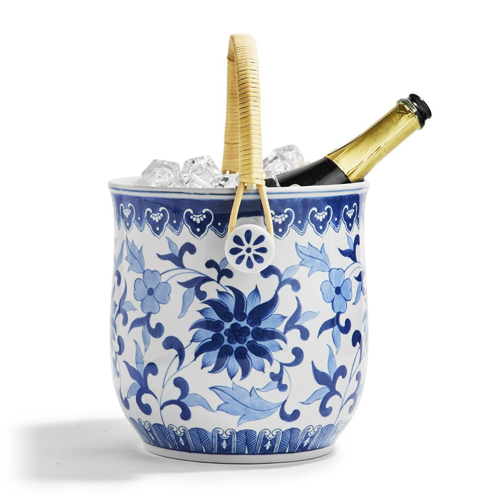 A blue and white floral ceramic ice bucket with a woven natural-fiber handle, filled with ice and a champagne bottle, on a white background.