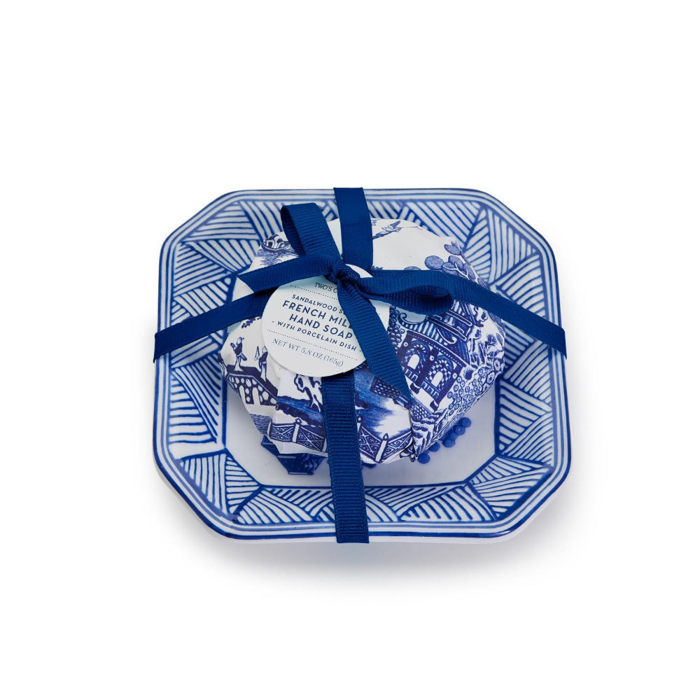 A round, blue and white porcelain tray with a soap bar embossed with a floral design, tied with a blue ribbon.