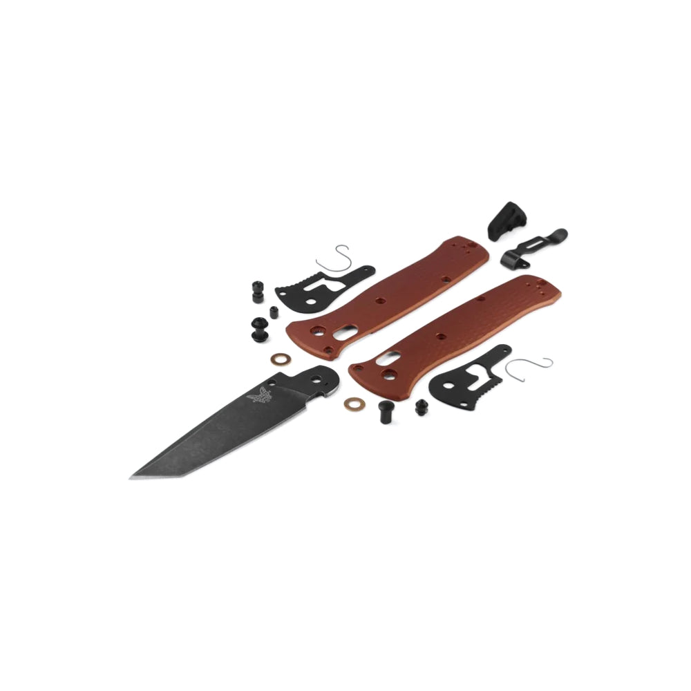 An exploded view of a folding knife showing its disassembled components, including two brown handle scales, a black blade, screws, washers, and black hardware, arranged neatly on a solid white background.