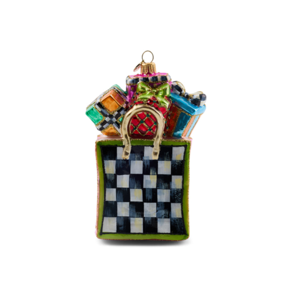 A decorative Christmas ornament shaped like a gift box with a black and white checkerboard pattern, green trim, and colorful gift packages spilling out from the top, shown on a plain white background.
