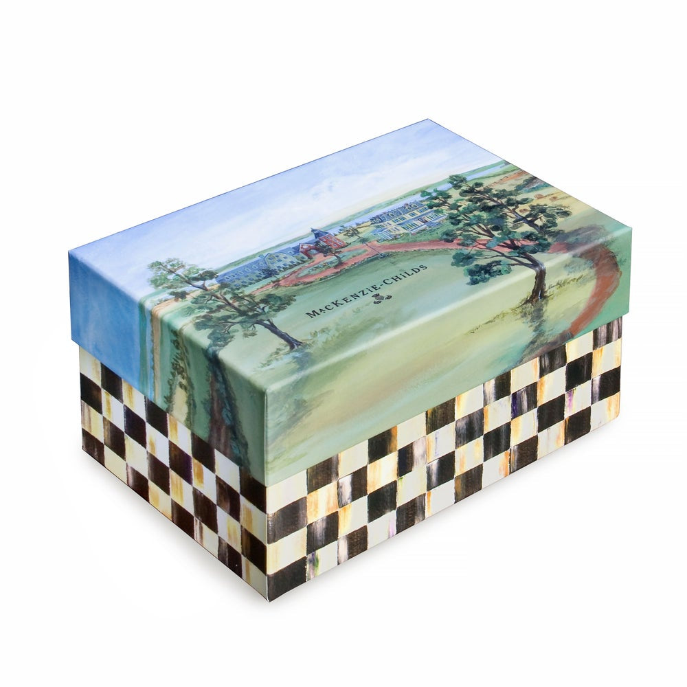 Ornament box with a black and white check and a colorful landscape scene on a white backround. 