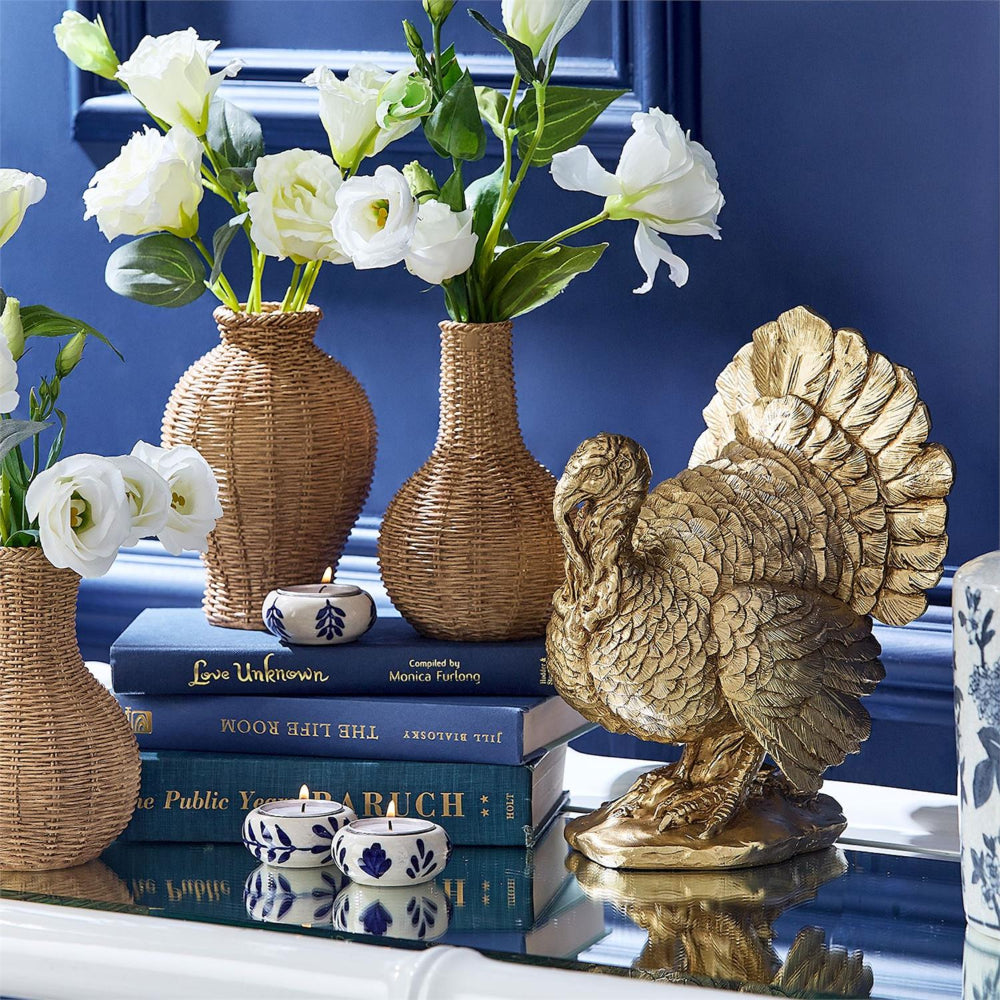 Decorative setup with gold rooster figurine, wicker vases, and white flowers against a blue background.