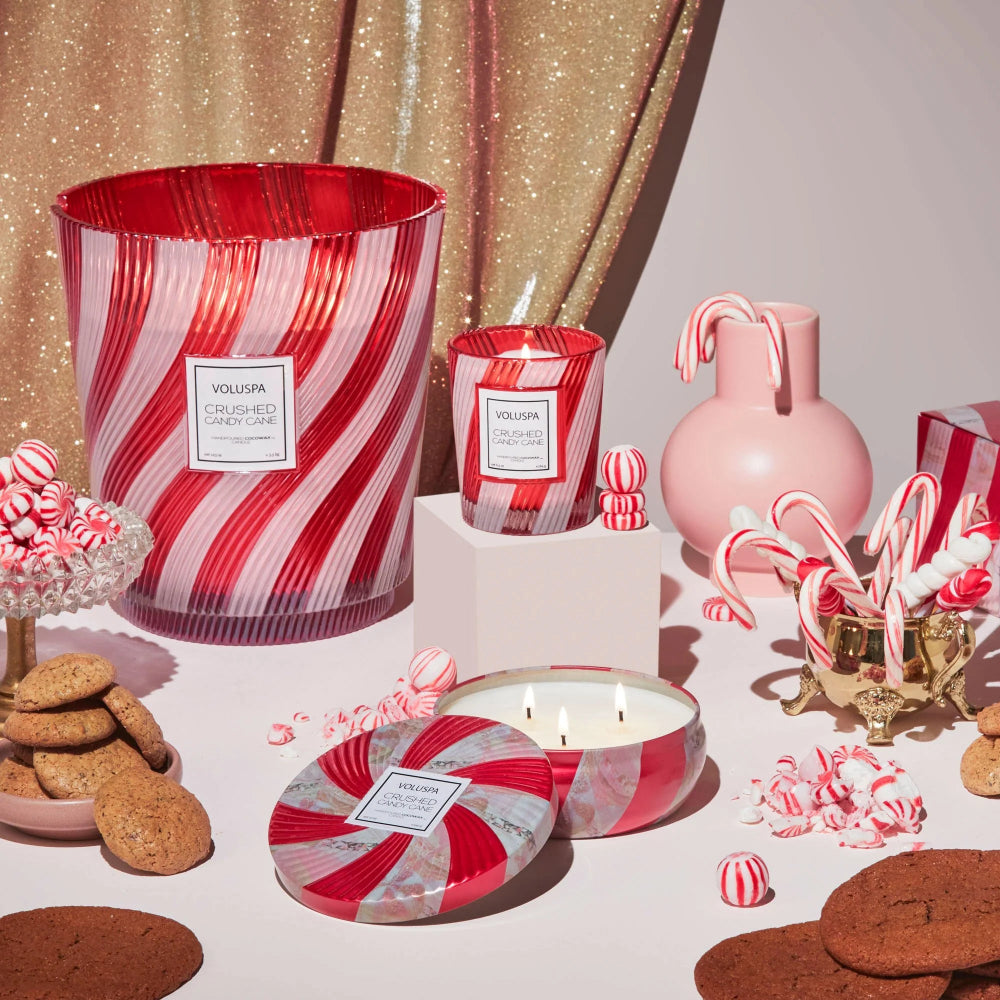 Decorative candles with red and white striped design on a table with cookies and candy canes.