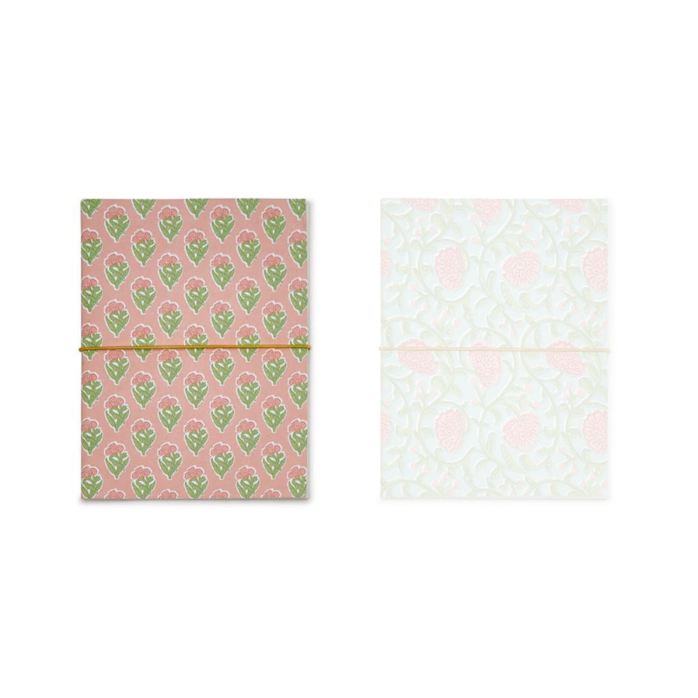 Pink paper back notebook with a pink background with a green floral pattern on a white backround. 