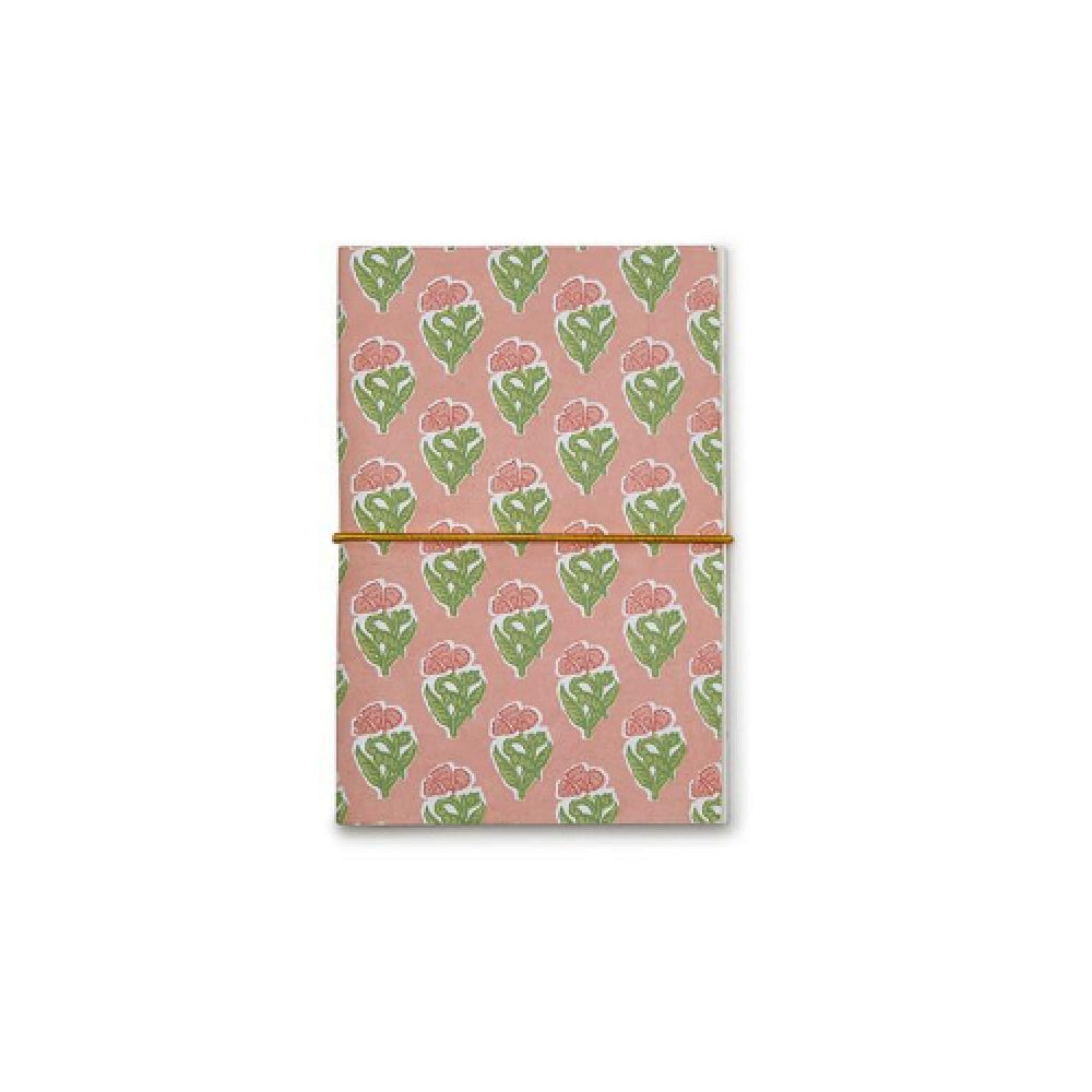 A notebook with a dusty pink cover featuring a repeating pattern of green leaves and pink flowers, secured with a thin gold elastic band, shown on a plain white background.