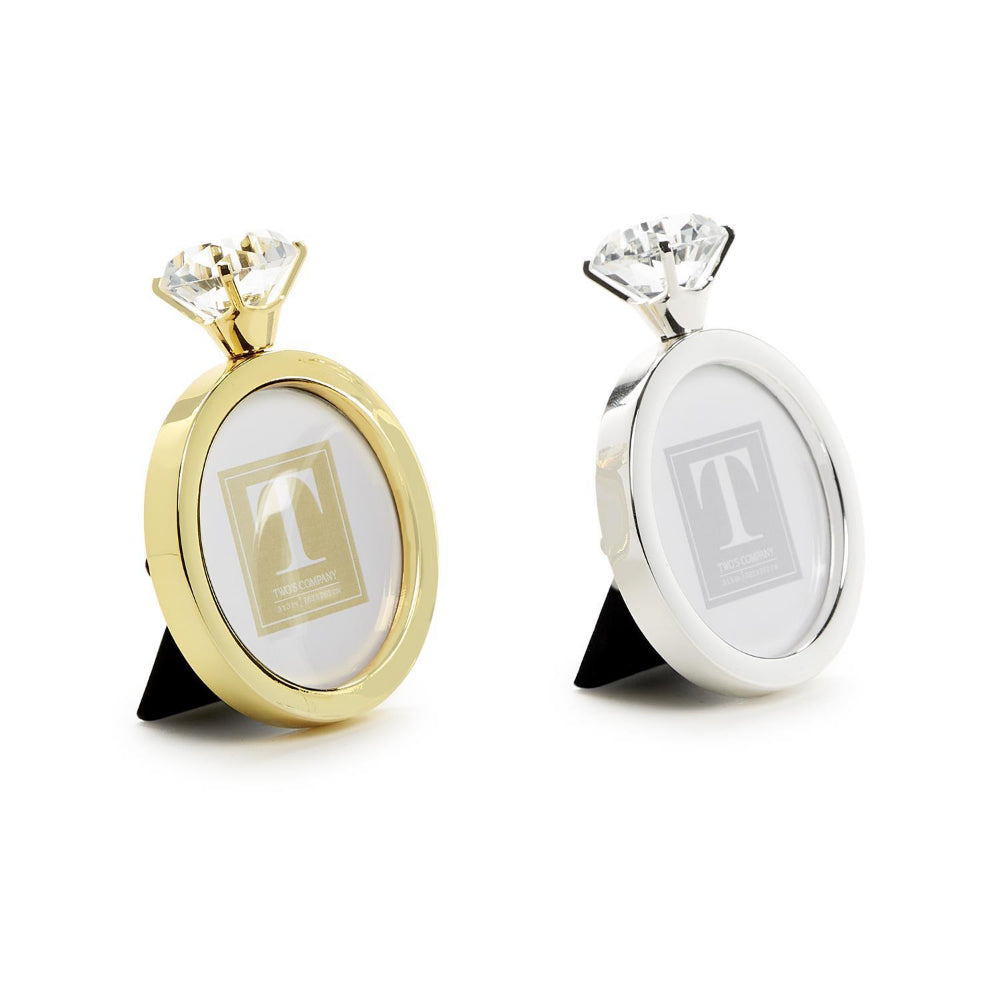 A angled side photo of two 3"x 3" round photo frames, one in gold and one in silver, each with a crystal diamond at the top on a white backround. 
