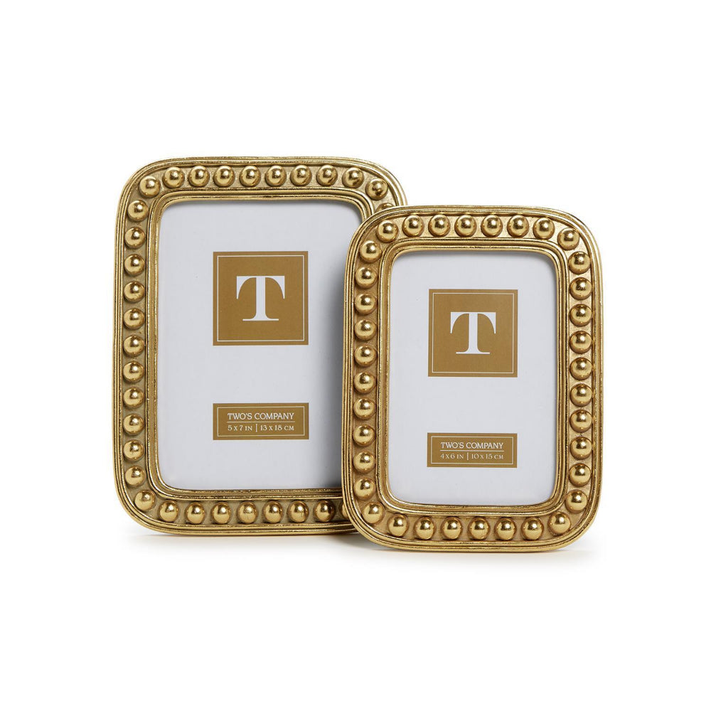 Two gold picture frames with decorative border in sizes: 4x6 & 5x7 on a white background.