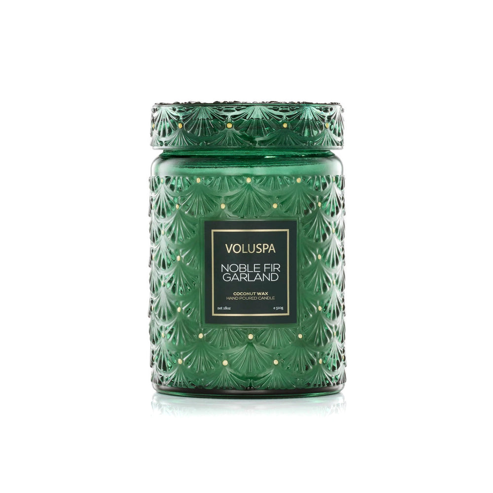A green textured glass jar candle with a matching lid, featuring a black label with gold text that reads 'VOLUSPA NOBLE FIR GARLAND'.