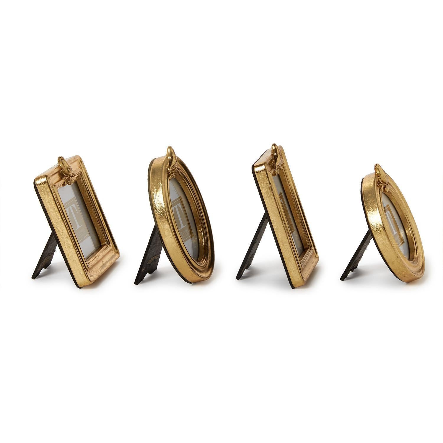 A photo of the side of four gold picture frames with a gold bird on the top in differant shapes on a white background.