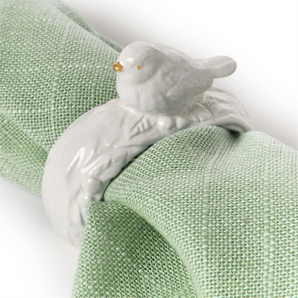 White ceramic bird-shaped napkin ring on a green napkin