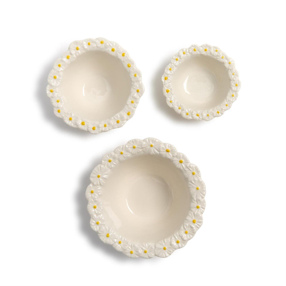 Three small, medium & large ceramic bowls with decorative daisy flower rims on a white background.
