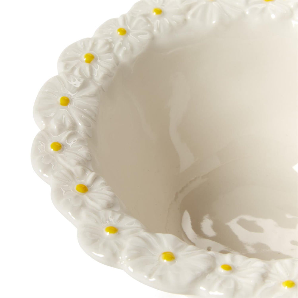 A close up of a white ceramic bowl a with daisy floral pattern on the rim with yellow centers on a white background.