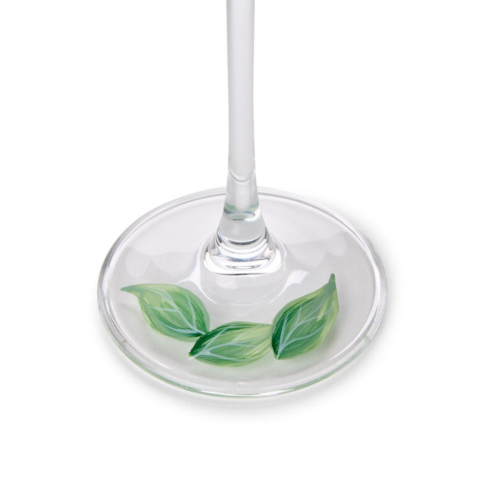 Clear glass champagne glass with a green leaf design on the base, on a white background.