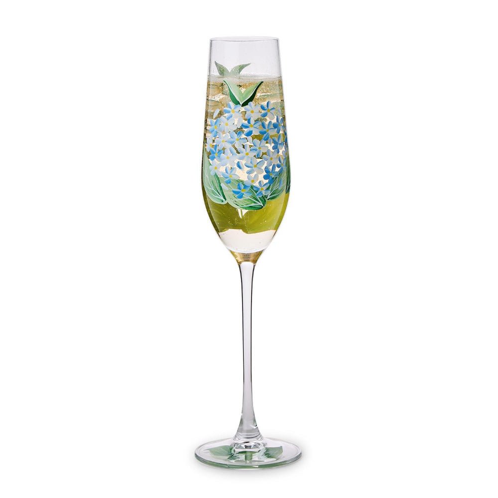 champagne flute with floral designs and champagene in it a white background.