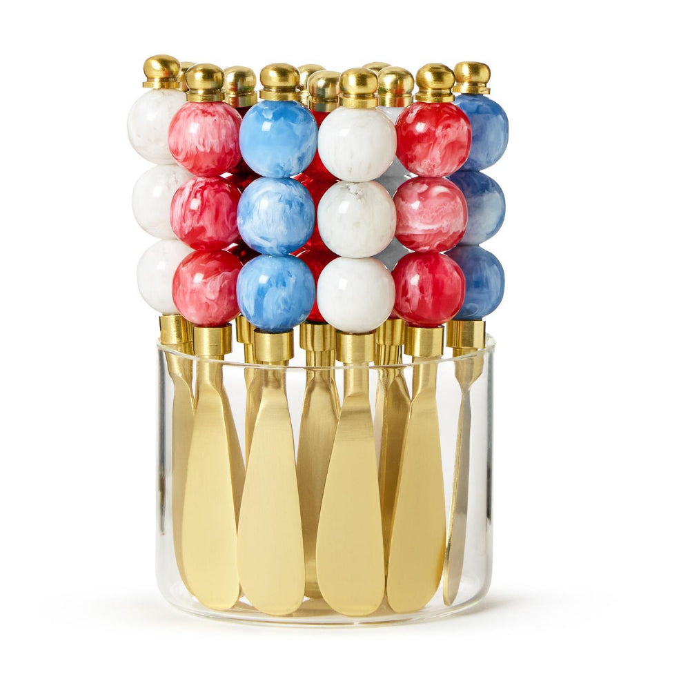 Gold cheese knives with colorful red, white and blue resin marble handles in a clear container on a white background