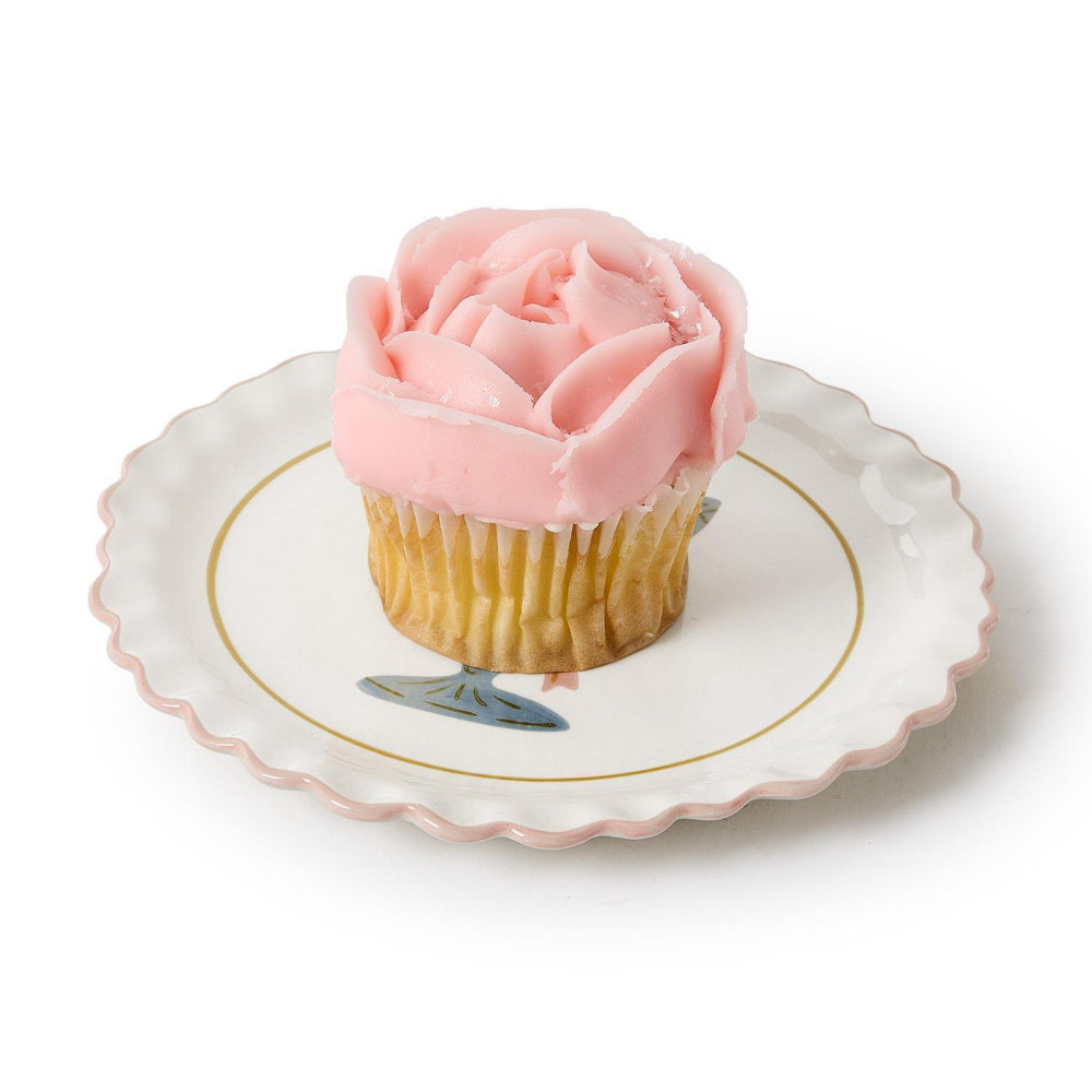 Cupcake with pink frosting on a decorative plate on a white backround. 