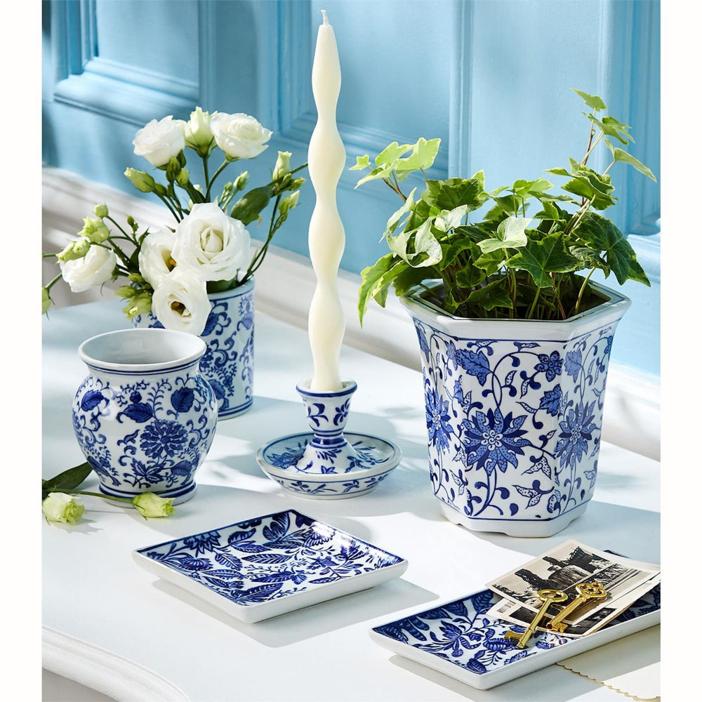 Decorative table setting with blue and white floral patterns on vases, plates, and a candle.