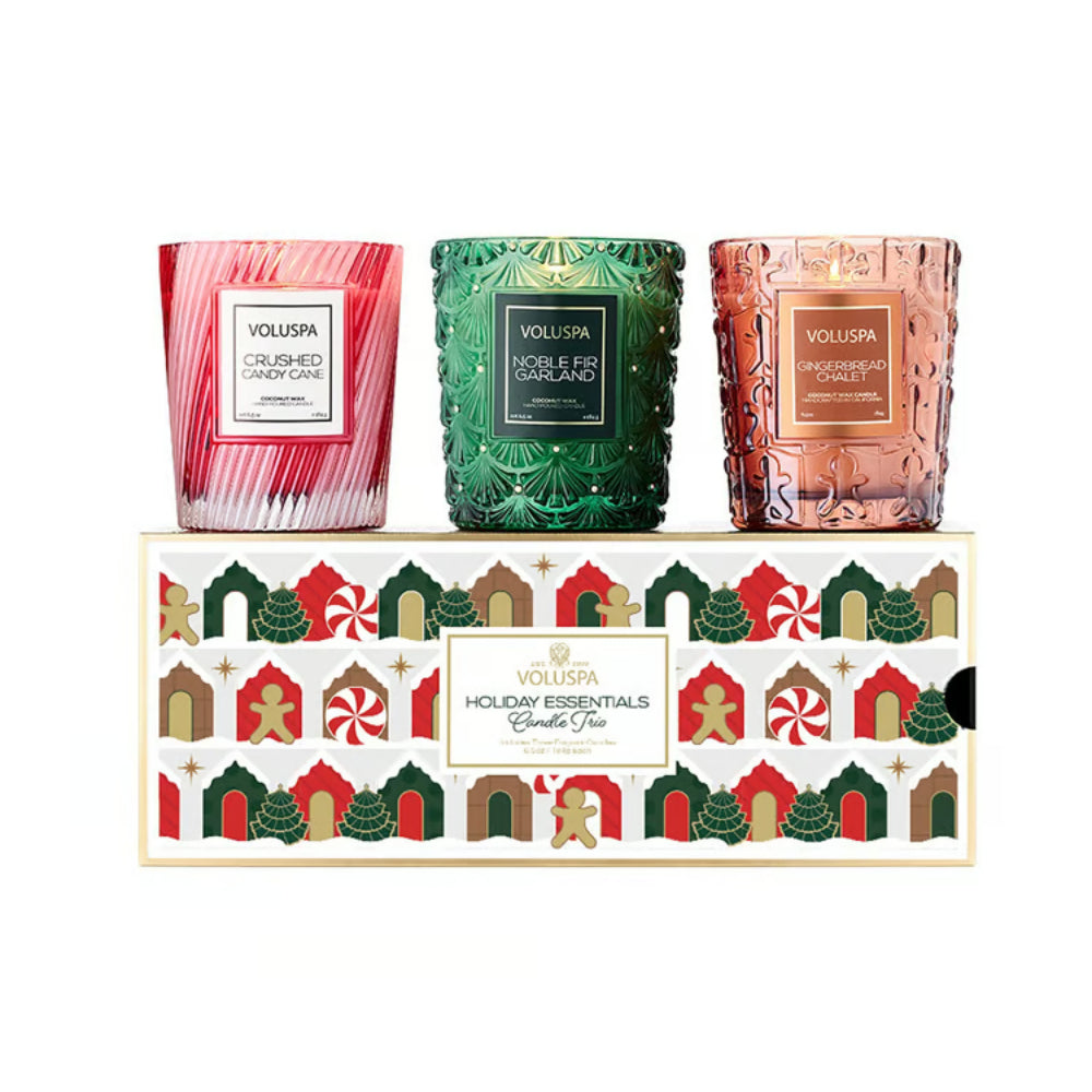 Three Voluspa scented candles in textured glass jars are displayed above their decorated gift box. The candles are in pink striped glass, green patterned glass, and rose gold patterned glass.