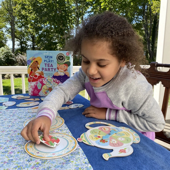 Child playing with a tea party playset on a table outdoors