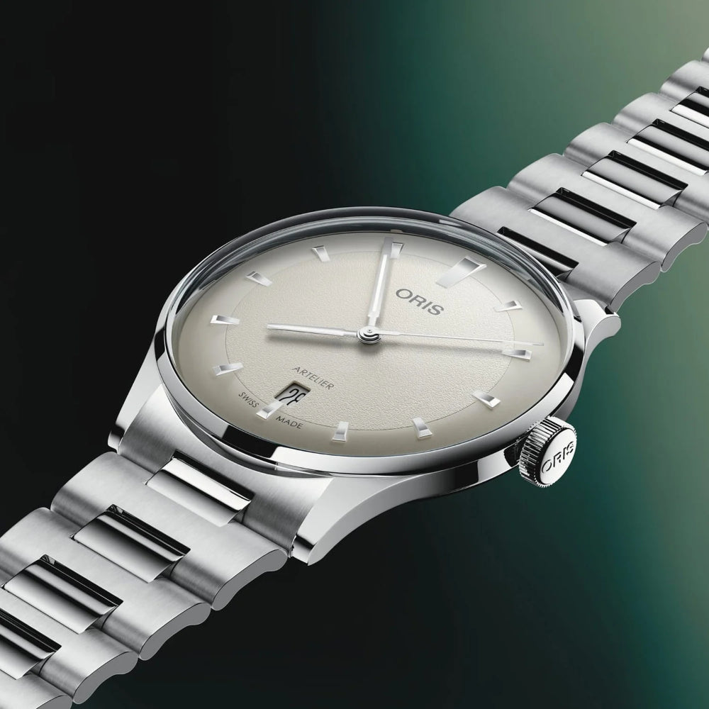 Oris Aequator watch with a silver stainless steel link bracelet, a silver case, and a champagne dial, shown on a dark green gradient background.