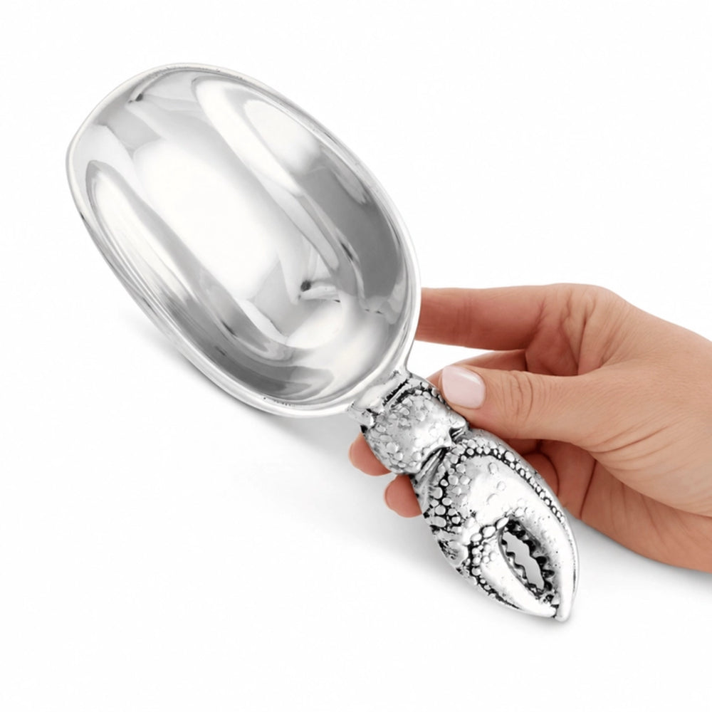 A silver metal scoop with a lobster-shaped handle, held by a hand against a plain white background.
