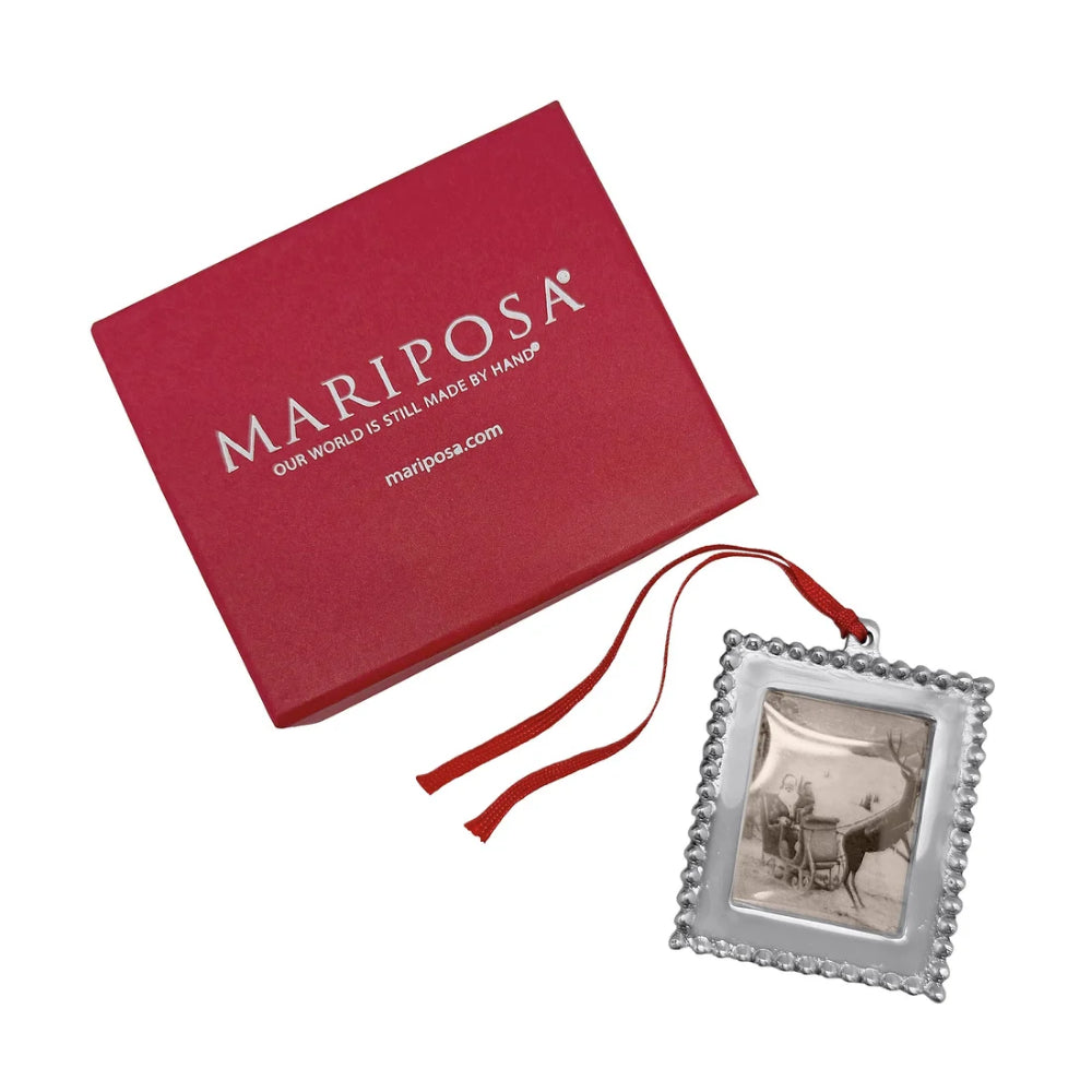 Beaded photo frame ornament with red hanger and red Mariposa box on a white backround. 