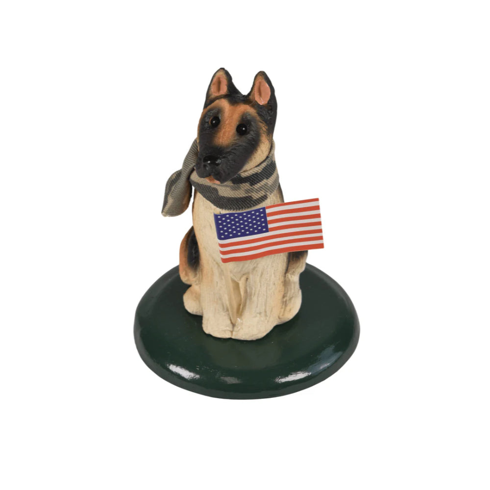 German shepard dog figurine with an american flag and camoflage bandana on a dark green base on a white background